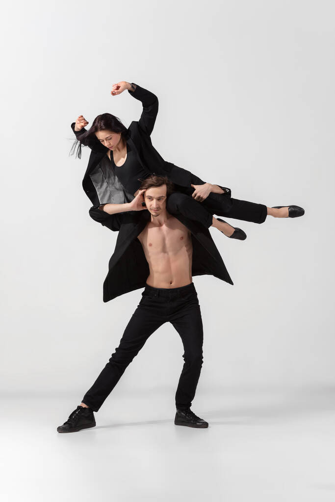 Jóvenes y elegantes bailarines de ballet en un estilo negro minimalista aislados sobre fondo blanco de estudio - Foto, imagen