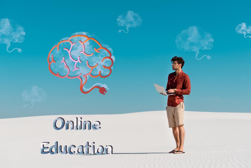 young man on sandy beach with laptop against clear blue sky, online education illustration - Photo, Image