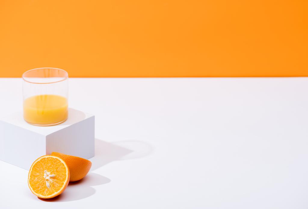friss narancslé üvegben, narancssárga alapon izolált fehér felületen érett narancs közelében - Fotó, kép