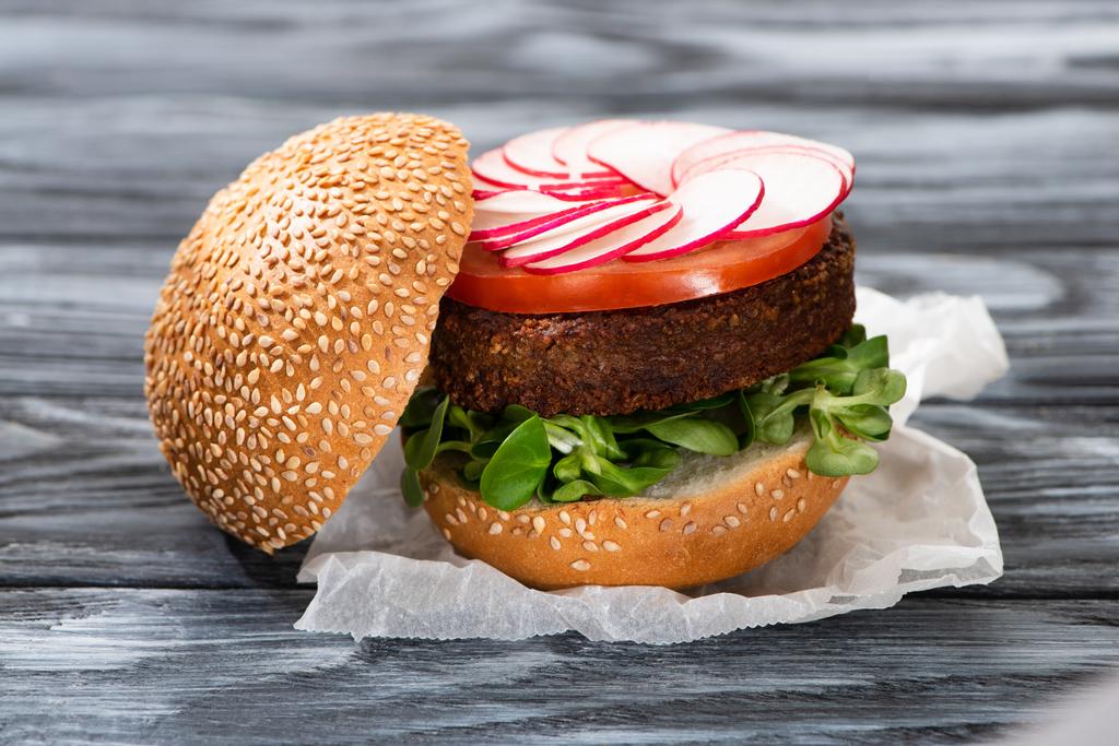 вкусный веганский бургер с редиской подается на деревянном столе
 - Фото, изображение