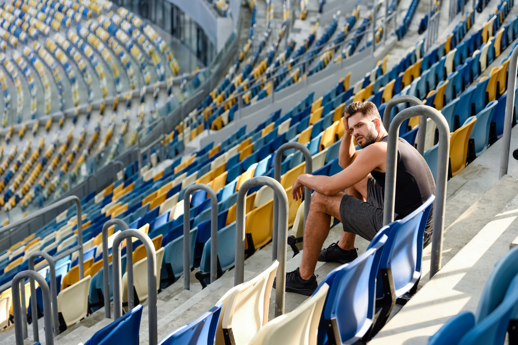 young sportsman sitting on stairs near seats at stadium - Photo, Image
