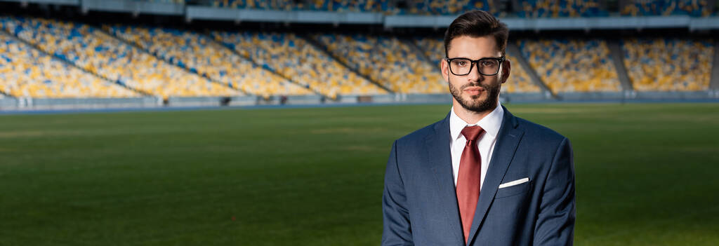 młody biznesmen w garniturze i okularach na stadionie, zdjęcie panoramiczne - Zdjęcie, obraz