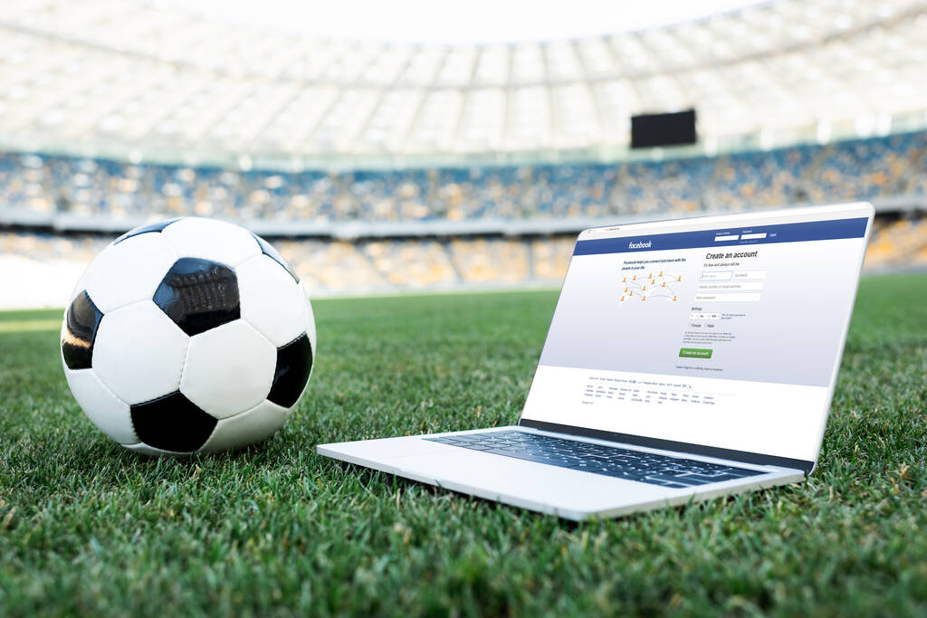 KYIV, UCRAINA - 20 GIUGNO 2019: pallone da calcio e laptop con sito facebook sul campo da calcio erboso dello stadio
 - Foto, immagini
