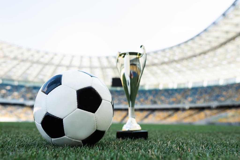 soccer ball and trophy on grassy football pitch at stadium - Photo, Image