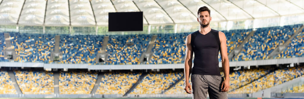 Stadyumdaki yakışıklı genç sporcu, panoramik çekim - Fotoğraf, Görsel
