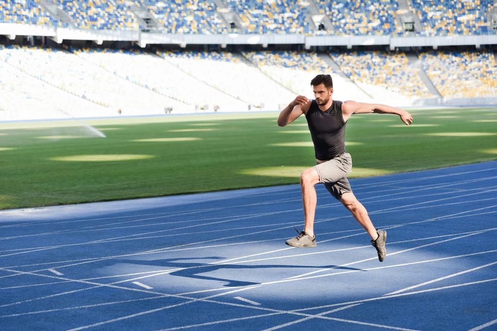 szybki przystojny biegacz ćwiczenia na bieżni na stadionie - Zdjęcie, obraz