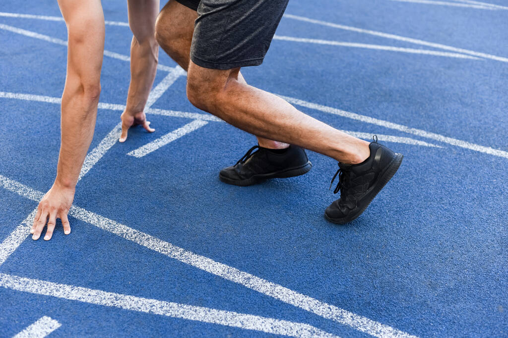 Stadyumdaki koşu pistinde koşucunun başlangıç konumundaki kırpılmış görüntüsü - Fotoğraf, Görsel