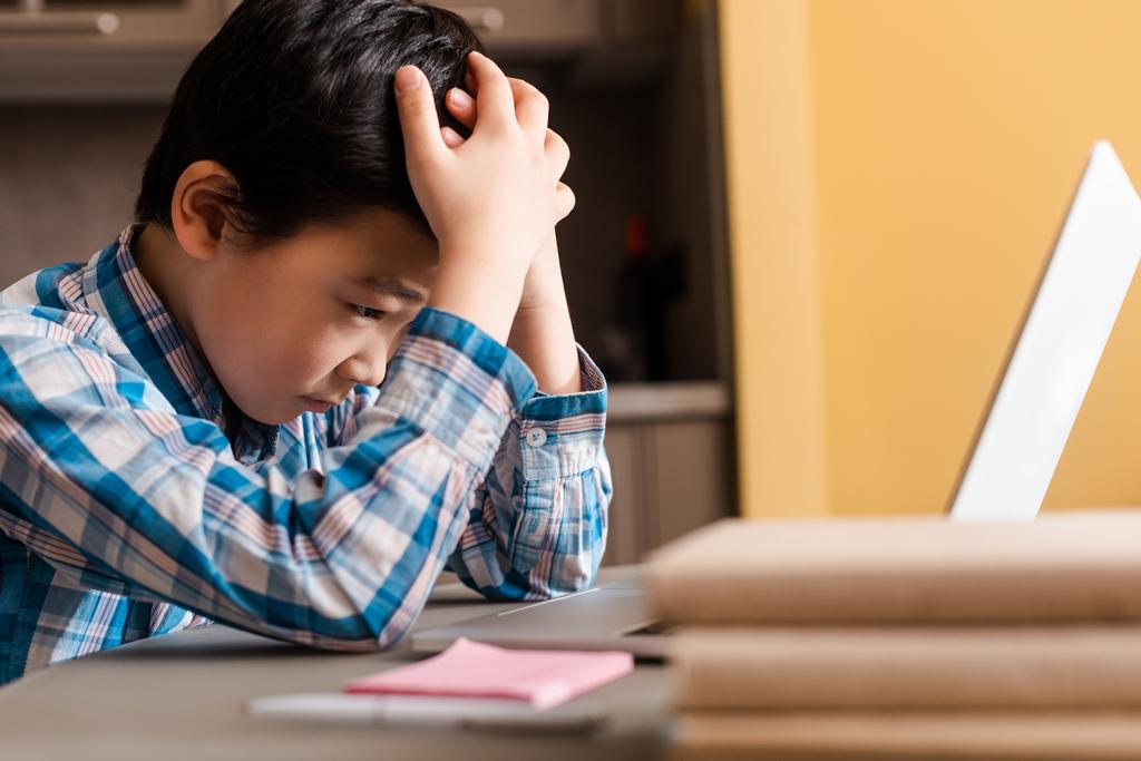 Печальный мальчик учится онлайн с ноутбуком дома во время карантина - Фото, изображение