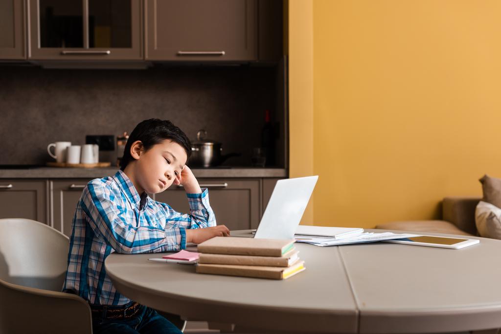 ασιατικό αγόρι σπουδάζει online με βιβλία και φορητό υπολογιστή στο σπίτι κατά τη διάρκεια της καραντίνας - Φωτογραφία, εικόνα