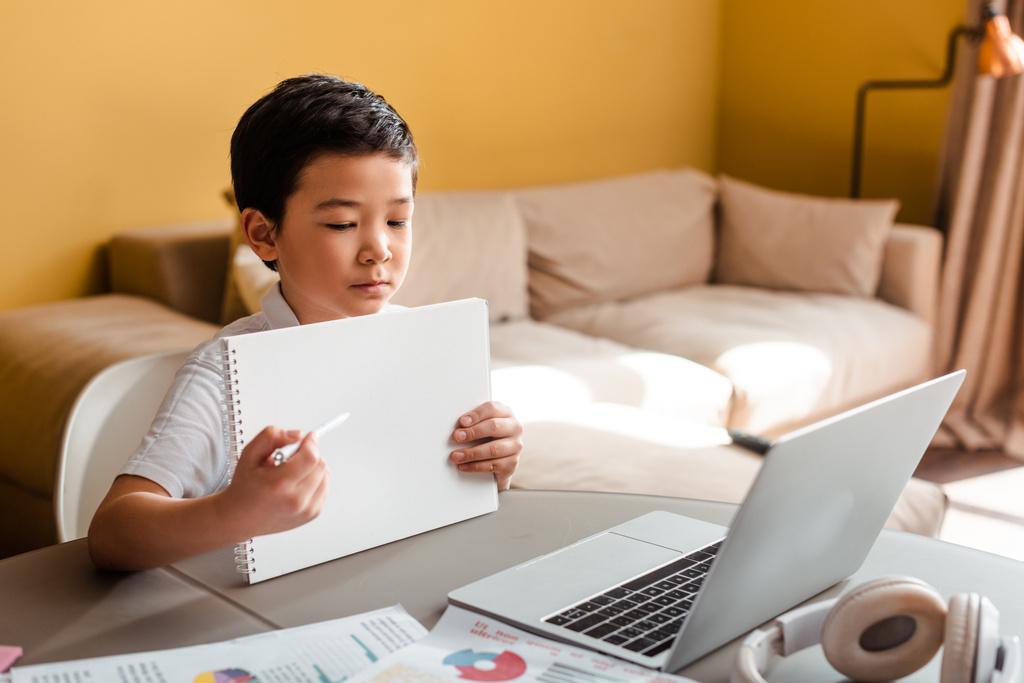 Asijský chlapec studuje on-line s poznámkovým blokem a notebookem doma během vlastní izolace - Fotografie, Obrázek