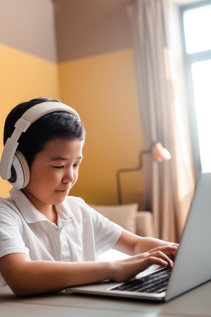 Asijský chlapec studuje on-line s notebookem a sluchátky doma během karantény - Fotografie, Obrázek