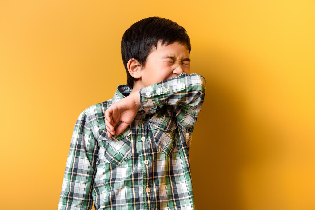 милий хворий азіатський хлопчик чхає на жовтому під час самоізоляції
 - Фото, зображення
