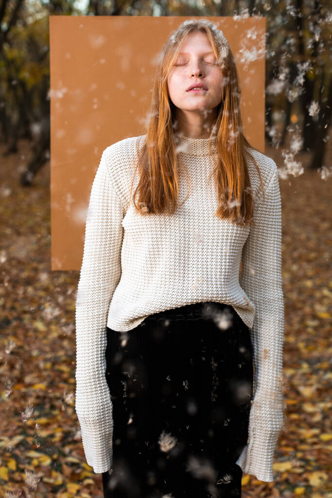 Vrouwelijk model in witte trui met vliegende fuzz - Foto, afbeelding
