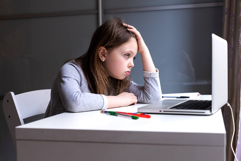 Väsynyt online-tietokoneluokkiin, lapsi katsoo monitoria surullisesti. Väsymys etäopetuksesta. Tyttö koulun läksyjen toteutuksessa. Koulutyttö kotona kannettavan kanssa
. - Valokuva, kuva