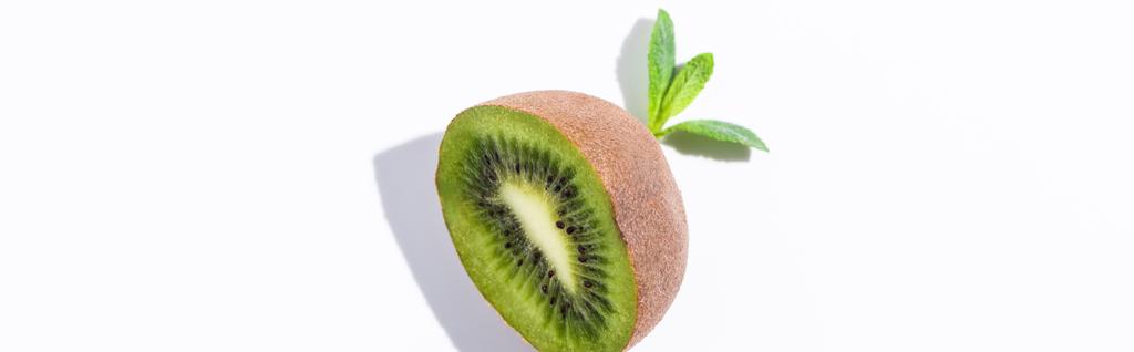 panoramisch concept van biologisch kiwi fruit half bij pepermunt bladeren op wit  - Foto, afbeelding