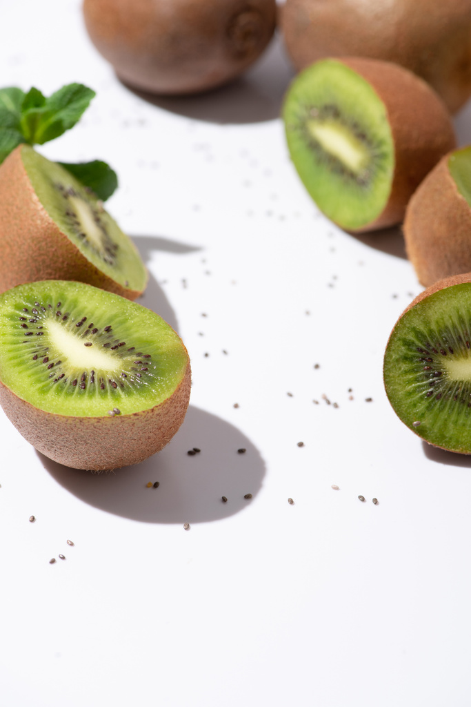 selektivní zaměření čerstvého ovoce kiwi v blízkosti bio máta peprná a černá semena na bílém  - Fotografie, Obrázek
