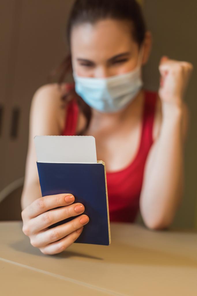 selective focus of happy woman in medical mask holding passport and air ticket - Photo, Image