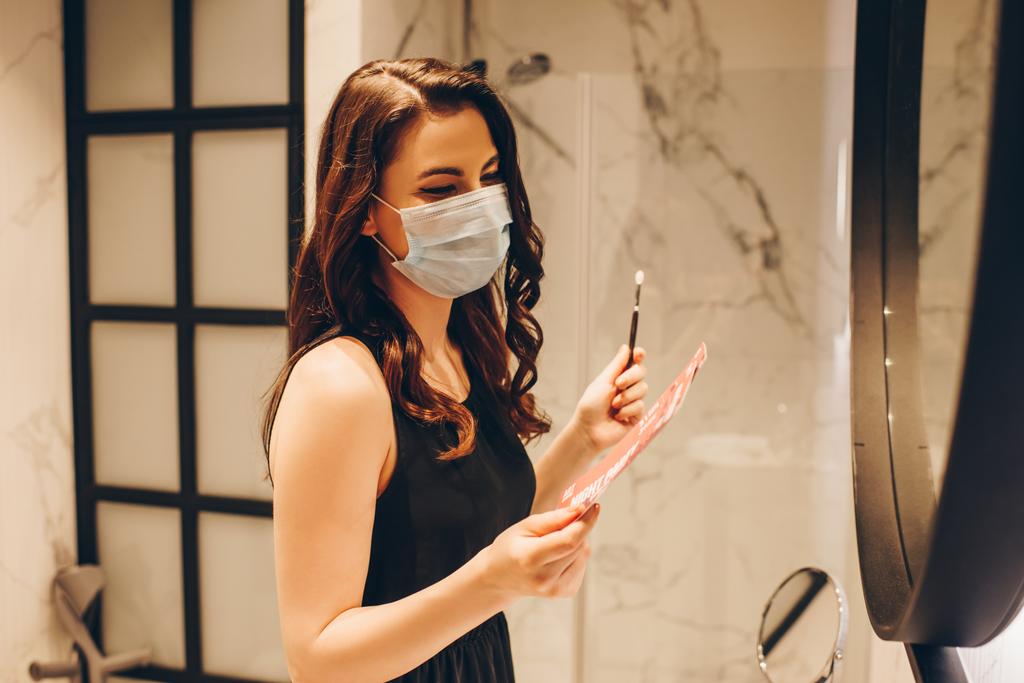 женщина в медицинской маске и черном платье с ночными билетами и косметической щеткой, конец карантинной концепции
  - Фото, изображение
