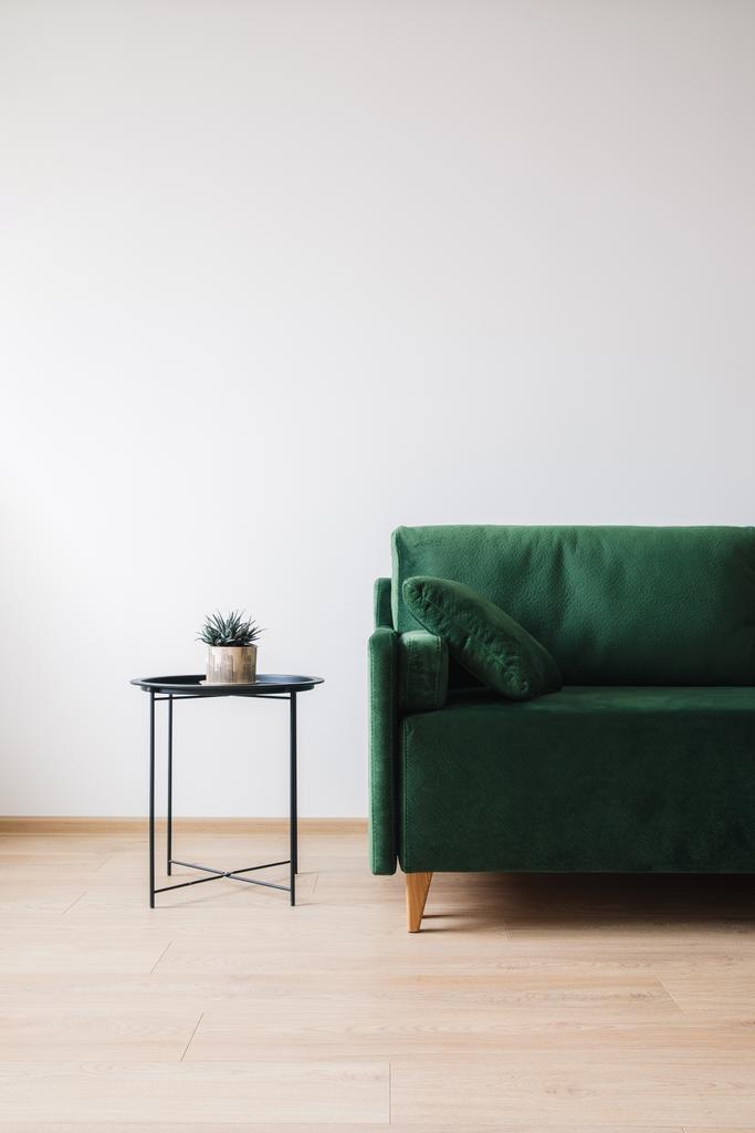 Yastıklı yeşil kanepe ve çiçekli kahve masası. - Fotoğraf, Görsel
