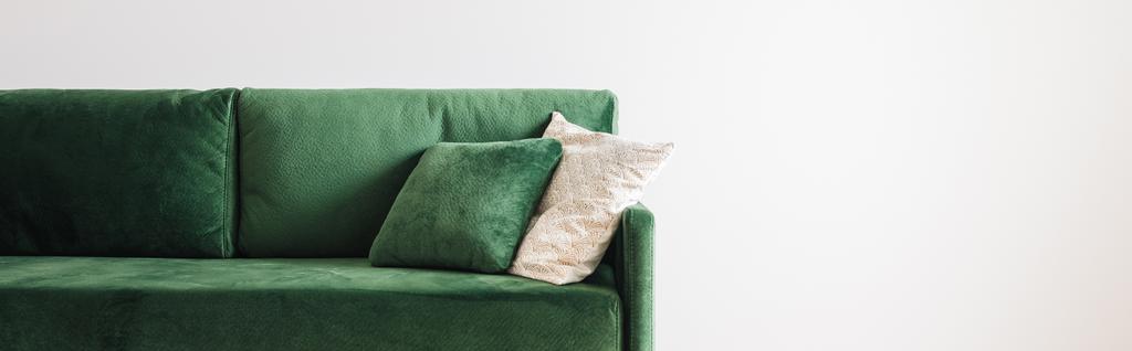 グレーの壁の近くの広々とした部屋に枕付きのモダンな緑のソファ、パノラマショット - 写真・画像