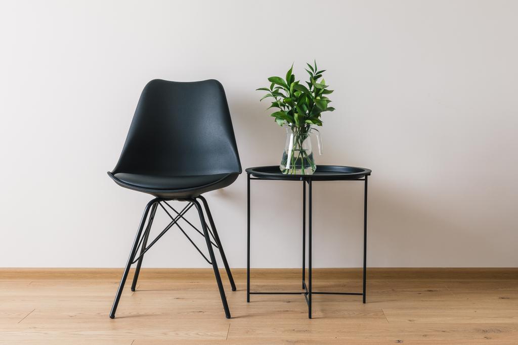 черный журнальный столик с зеленым растением рядом с современным стулом
 - Фото, изображение
