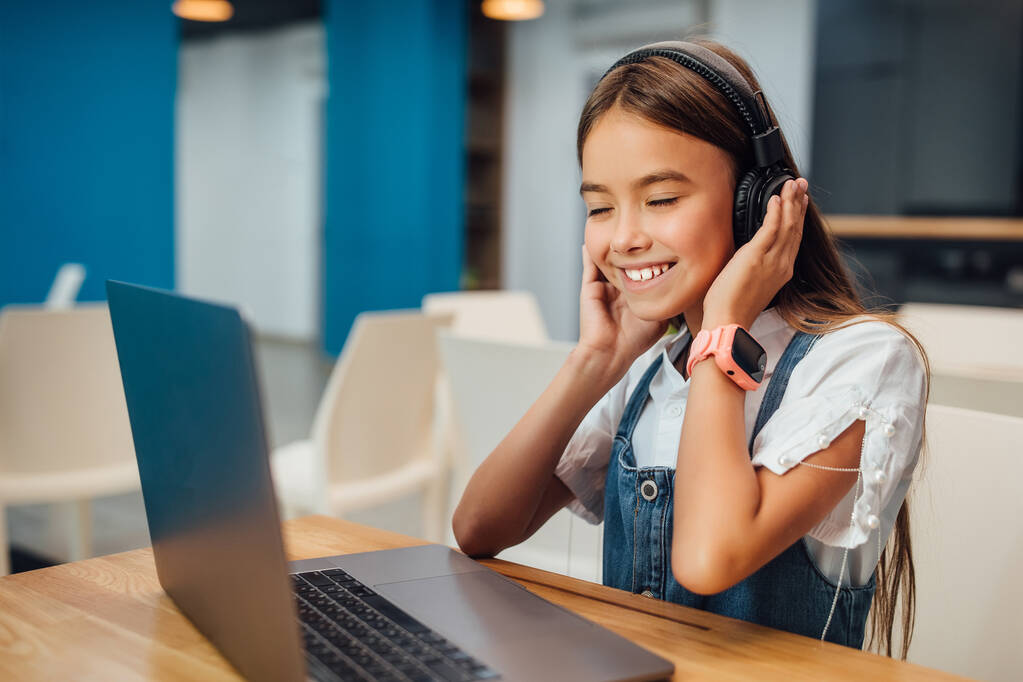 Laptopot és fejhallgatót használó lány a modern iskolában. - Fotó, kép