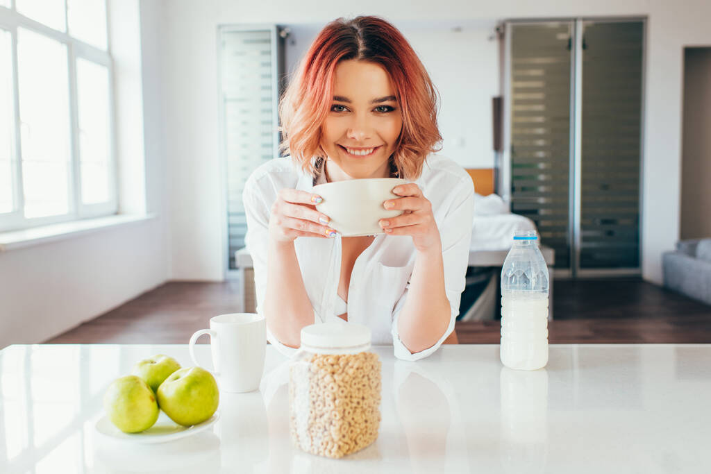 boldog lány eszik kukoricapelyhet tejjel reggelire karantén alatt  - Fotó, kép