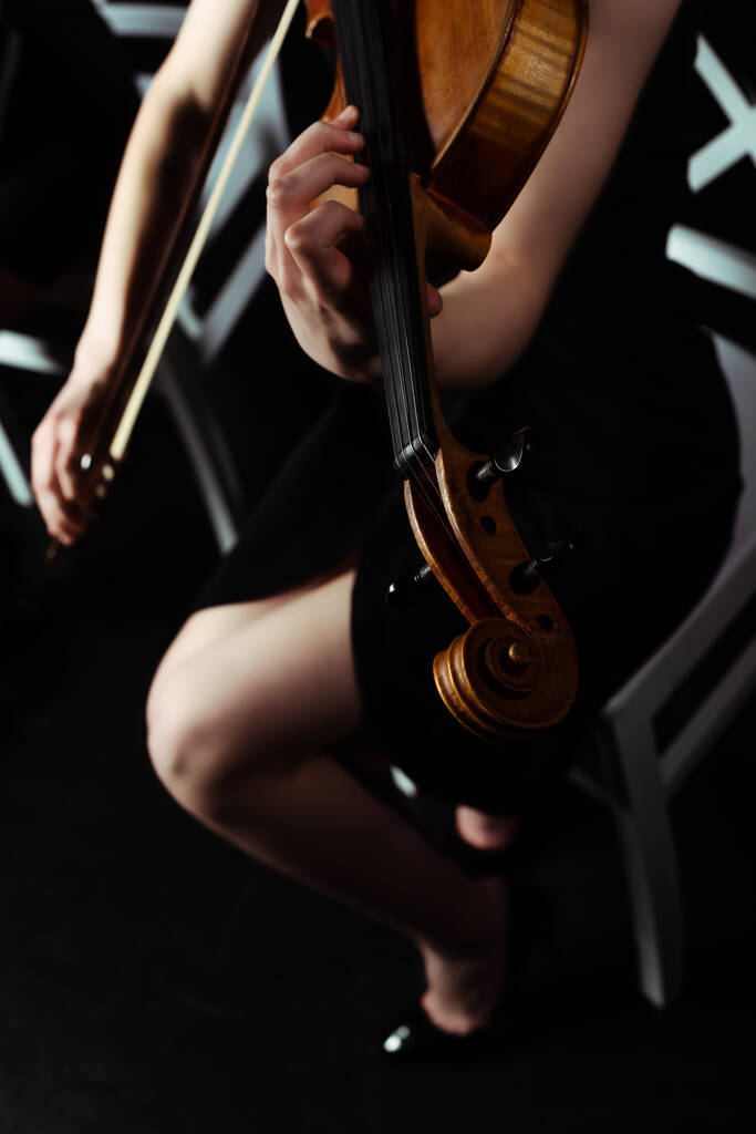 vista recortada de la música femenina tocando el violín en el escenario oscuro
 - Foto, imagen