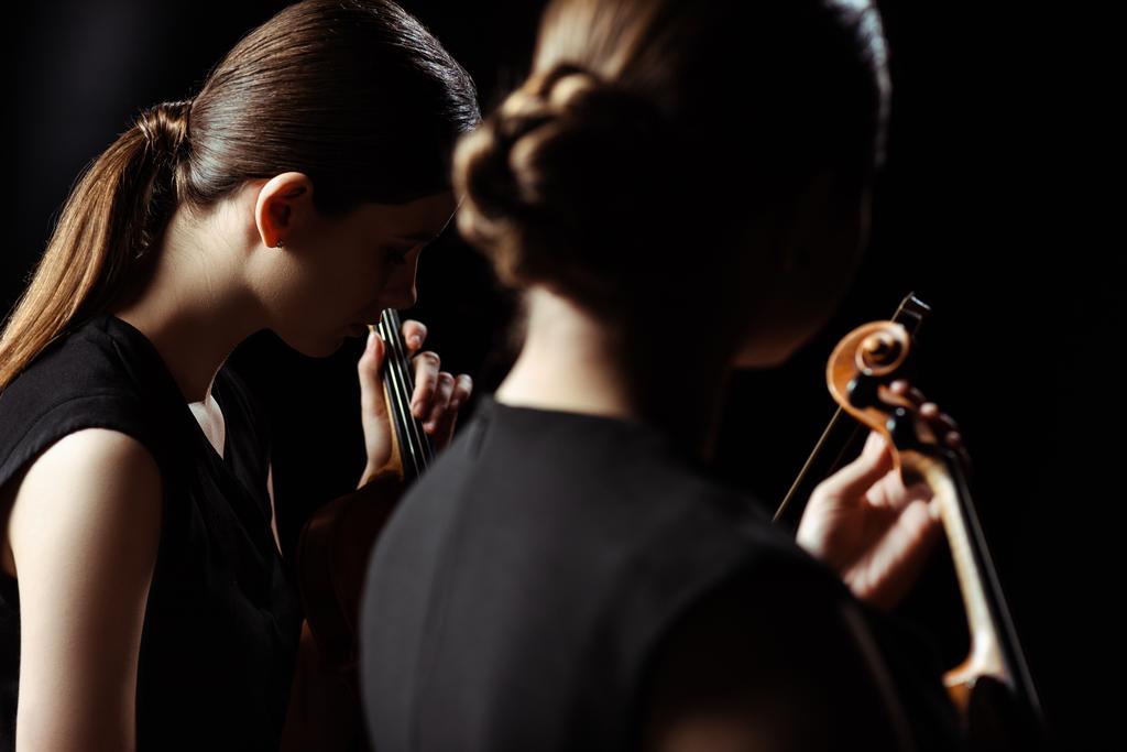 ammattimuusikot soittamassa klassista musiikkia viuluilla pimeällä näyttämöllä
  - Valokuva, kuva