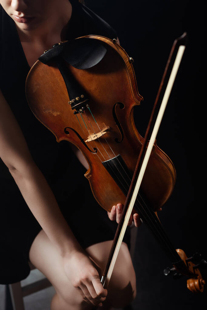 vágott kilátás professzionális női zenész játszik hegedűn a sötét színpadon - Fotó, kép