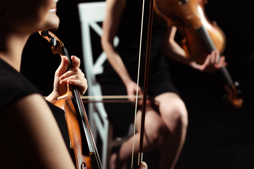 Teilansicht professioneller Musikerinnen auf Geigen auf dunkler Bühne, selektiver Fokus - Foto, Bild