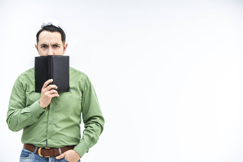 Зрілий бізнесмен заглядає над чорним ноутбуком з підозрілим, нечистим виразом обличчя на білому тлі з копійкою для тексту або продукту
. - Фото, зображення