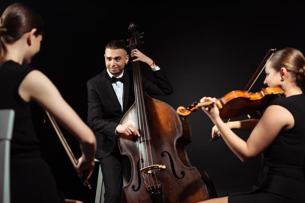 trio di musicisti felici che suonano al contrabbasso e violini isolati sul nero
 - Foto, immagini