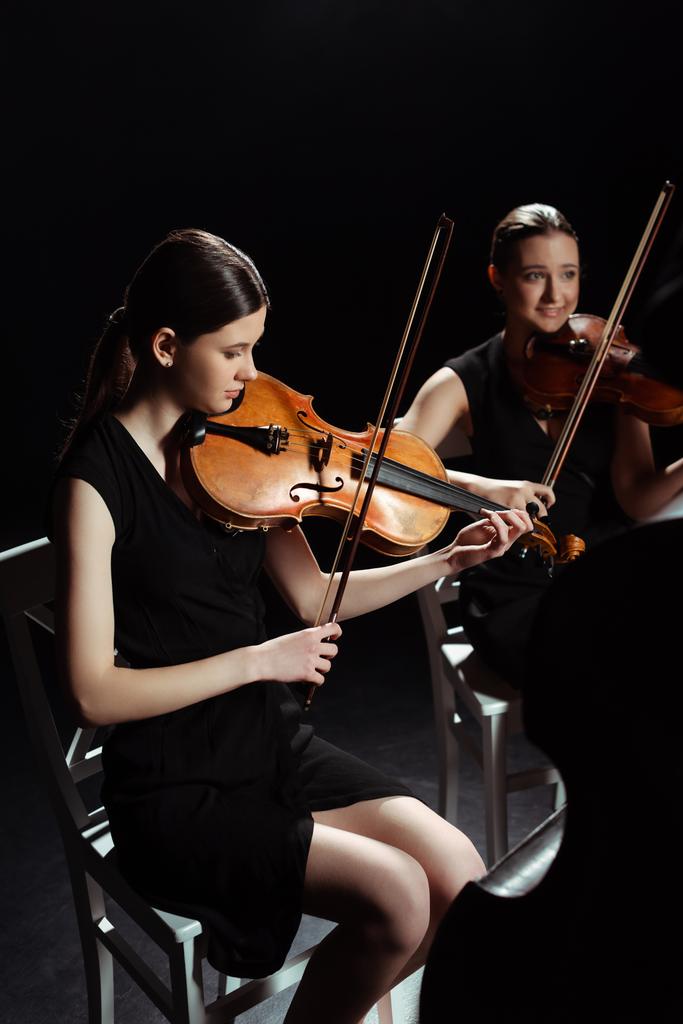 de beaux musiciens professionnels jouant de la musique classique sur violons sur scène sombre
  - Photo, image
