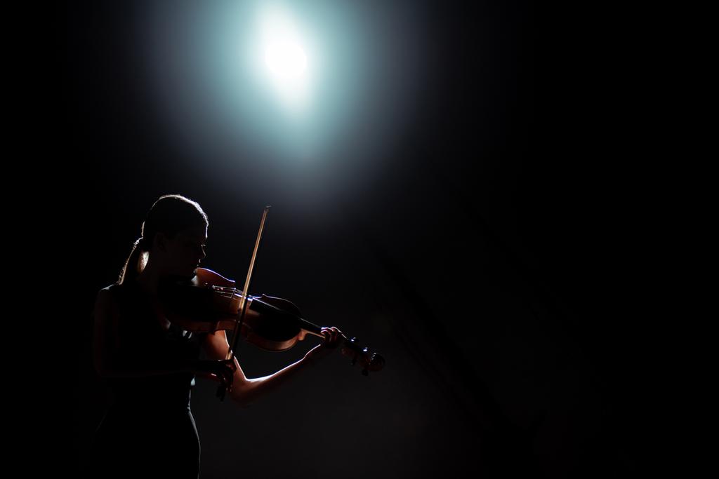 sylwetka kobiecego muzyka grającego na skrzypcach na ciemnej scenie z podświetleniem - Zdjęcie, obraz