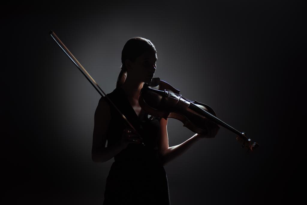 силует професійної жінки-музикантки, що грає на скрипці на темній сцені
 - Фото, зображення