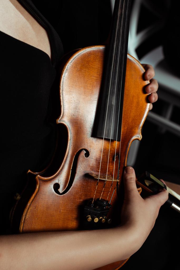 cropped view of female musician holding violin on dark stage - Photo, Image