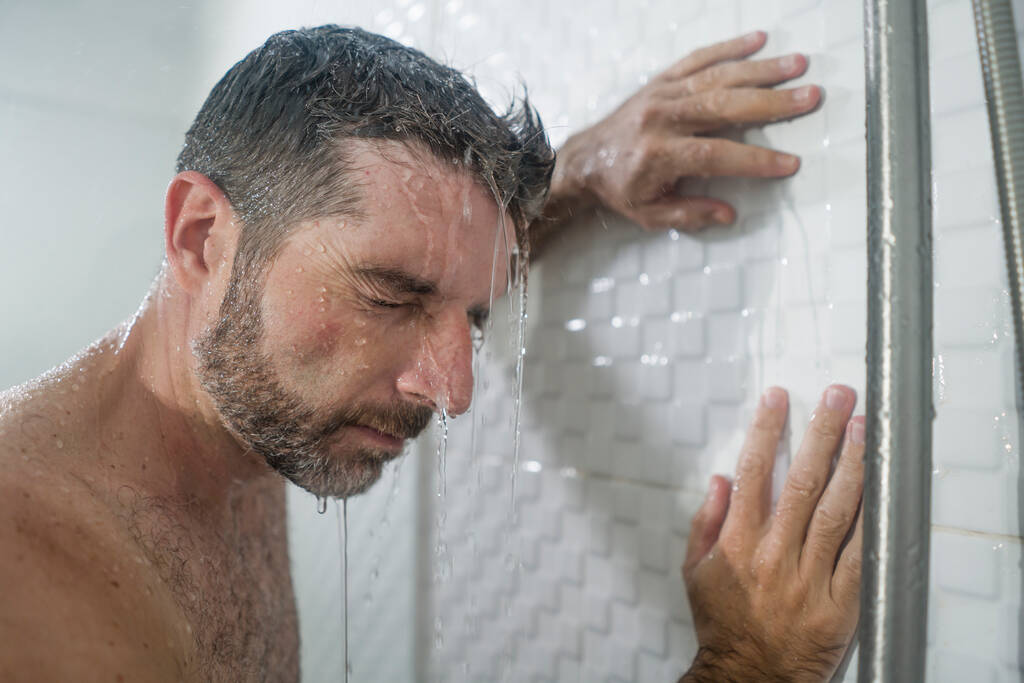 cuarto de baño en casa retrato dramático de joven atractivo hombre triste y deprimido en la ducha apoyado contra la pared sensación reflexiva abrumado por el problema de la vida
  - Foto, Imagen