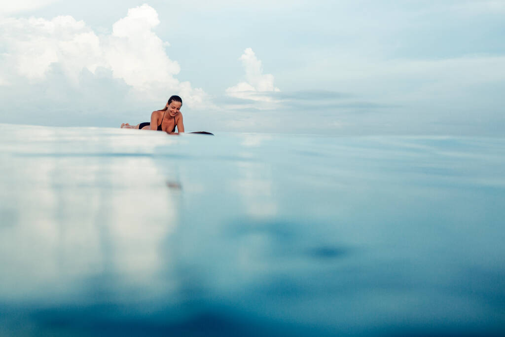 Прекрасна дівчина сидить на дошці в океані. На чудовому острові Балі. - Фото, зображення