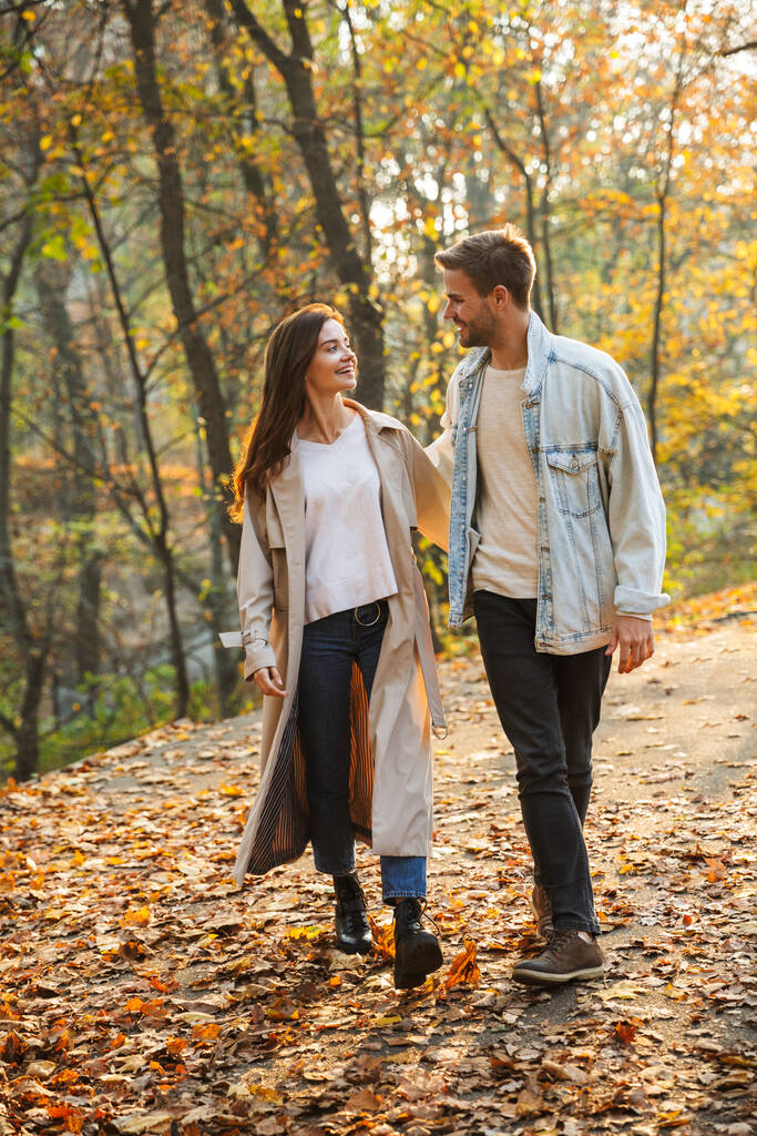 Pleine longueur d'un beau jeune couple amoureux marchant au parc d'automne, se tenant la main
 - Photo, image