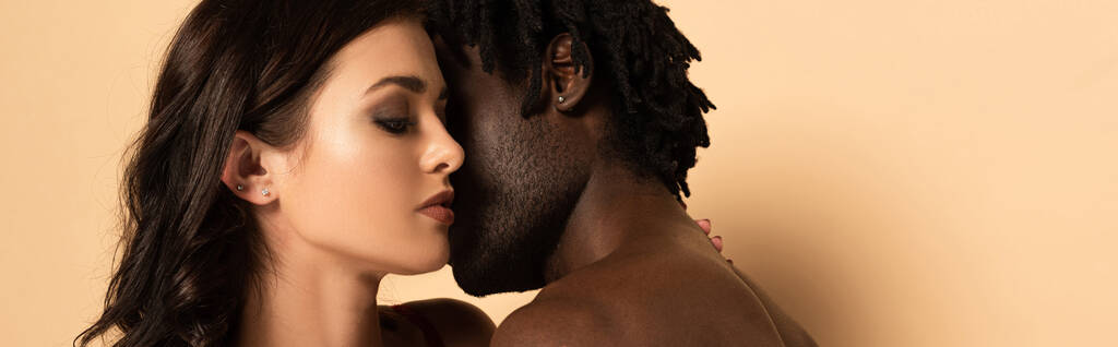 beautiful sensual interracial couple hugging on beige, horizontal crop - Photo, Image