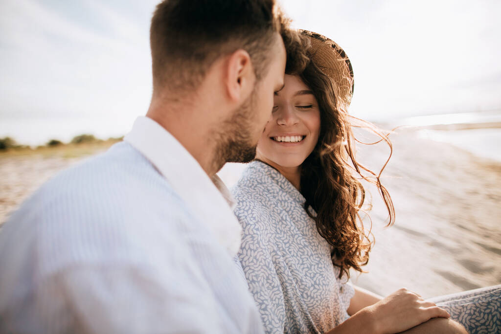 Lua-de-mel numa ilha deserta. Jovem casal sentado na praia e sorrindo
 - Foto, Imagem