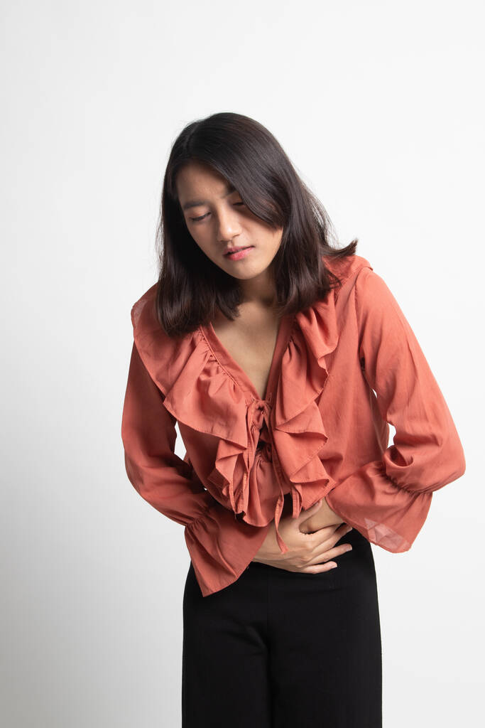 Genç Asyalı kadın mide ağrısı beyaz arka plan üzerinde var - Fotoğraf, Görsel