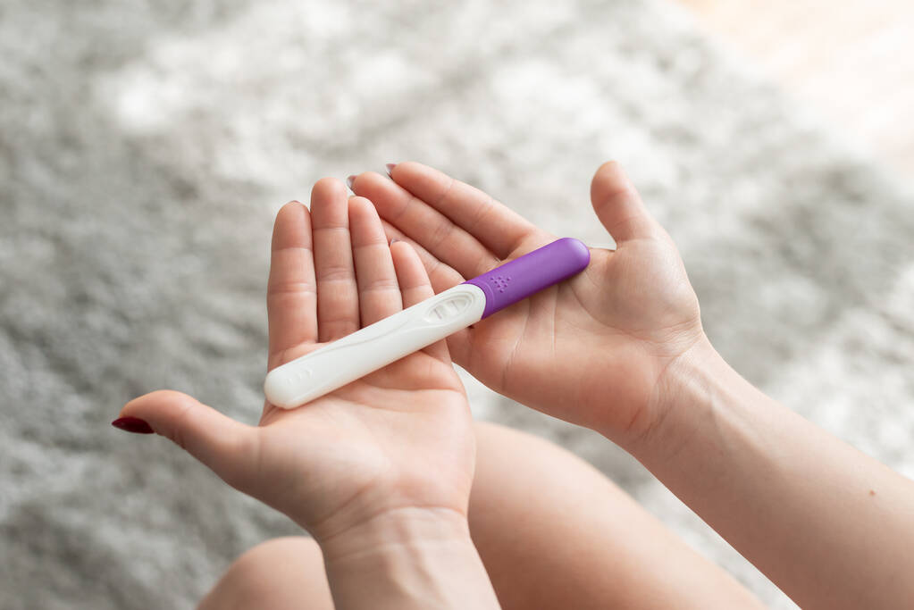 Primer plano de la mano de la mujer que sostiene una prueba de embarazo en casa positiva
. - Foto, Imagen