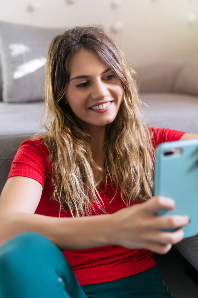 γυναίκα χαμογελώντας χρησιμοποιώντας το smartphone στο σπίτι - Φωτογραφία, εικόνα