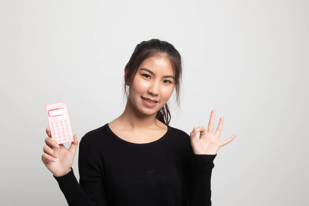Азіатський жінка Показати ОК з калькулятором на білому тлі - Фото, зображення