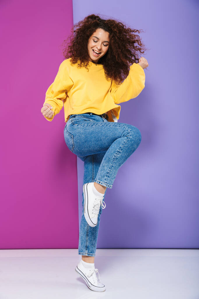 Full length image of pretty happy curly woman swearing casual clothes smiling and rejoicing isolated over purple background - Photo, Image