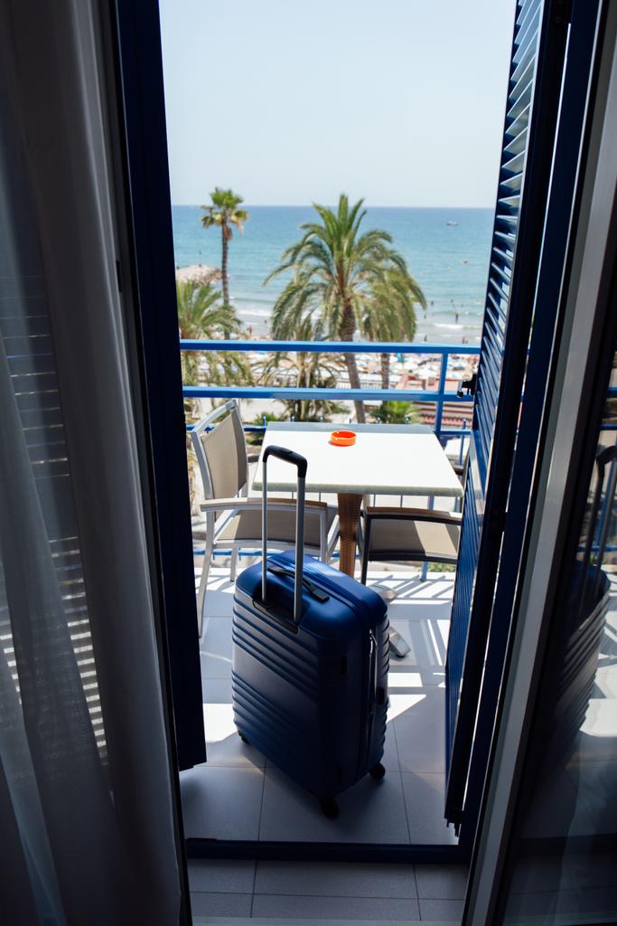 Valise sur balcon avec palmiers et paysage marin en arrière-plan en Catalogne, Espagne
  - Photo, image