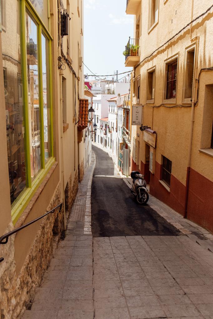 Skútr v blízkosti budov na chodníku městské ulice v Katalánsku, Španělsko  - Fotografie, Obrázek