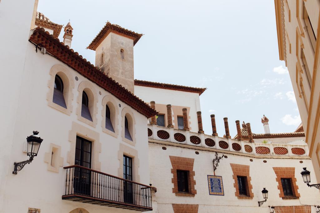 Niedrigwinkel-Ansicht von Straßenlaternen an Fassaden von Gebäuden mit blauem Himmel im Hintergrund in Katalonien, Spanien  - Foto, Bild